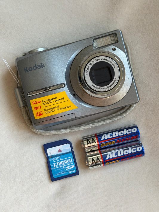 Kodak EasyShare C813 digital camera in gray with batteries and memory card laid flat