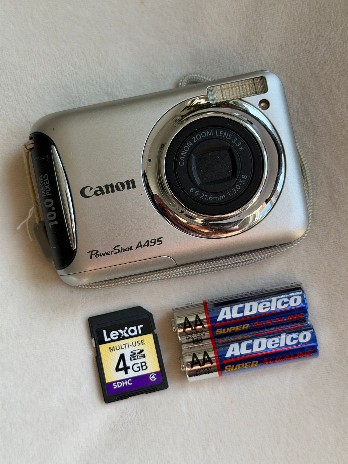 Canon PowerShot A495 digital camera in silver with batteries and memory card laid flat