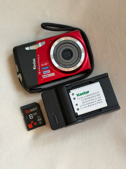 Kodak EasyShare M530 digital camera in red with battery, charger and memory card laid flat
